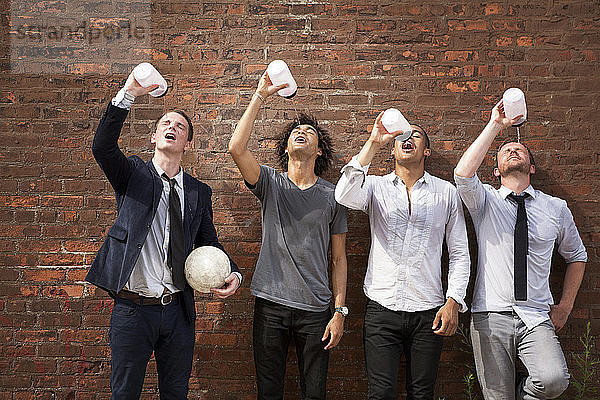 Freunde trinken Wasser  während sie an einer Ziegelmauer stehen