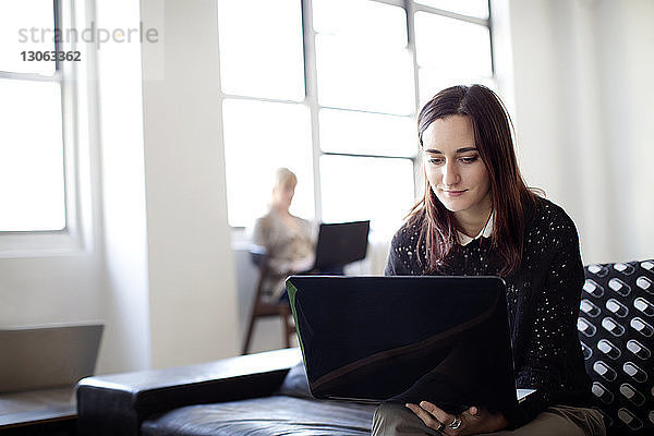 Junge Geschäftsfrau benutzt Laptop im Kreativbüro