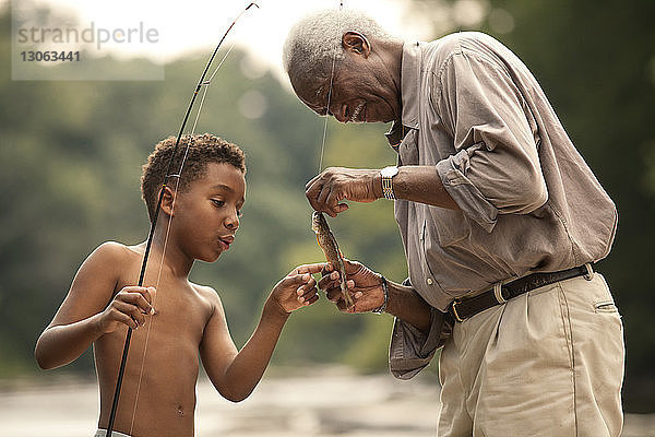 Grossvater und Enkel betrachten mit der Rute gefangene Fische