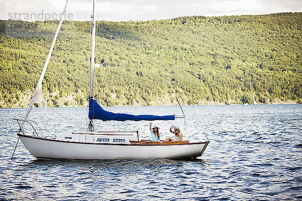 Freunde  die im Boot auf dem See gegen den Hügel fahren