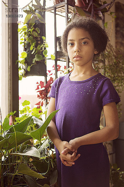 Porträt eines selbstbewussten Mädchens  das zu Hause bei Pflanzen steht