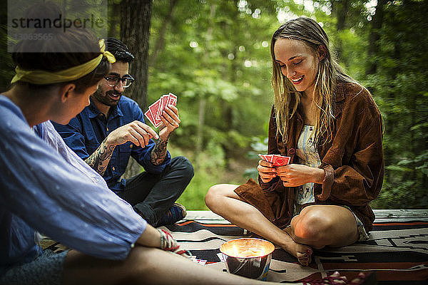 Freunde spielen Kartenspiel  während sie auf einer Veranda im Wald sitzen