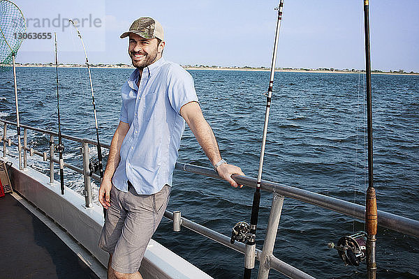 Porträt eines lächelnden Mannes auf einem Boot vor klarem blauen Himmel