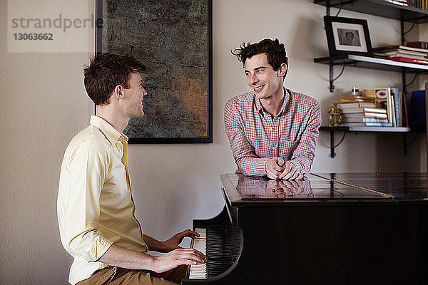 Schwuler Mann schaut seinen Klavier spielenden Freund an