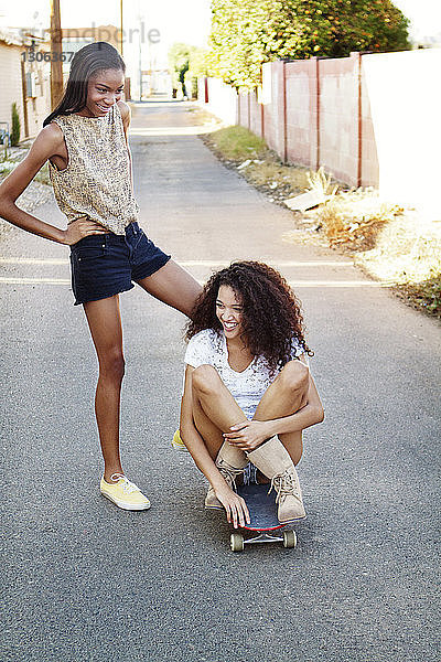 Glückliche Freunde mit Skateboard auf der Straße in der Stadt