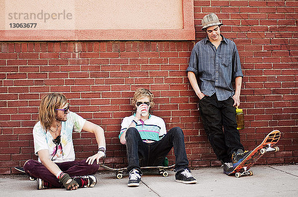 Freunde mit Skateboard entspannen sich an der Ziegelmauer