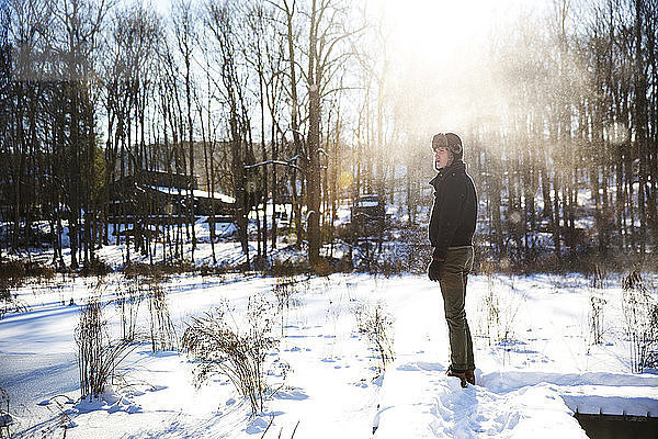 Mann schaut weg  während er auf schneebedecktem Feld steht