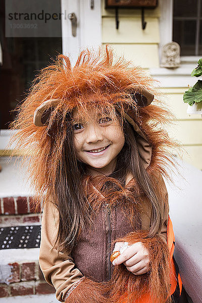 Porträt eines lächelnden Mädchens in Halloween-Kostüm  das vor dem Haus steht