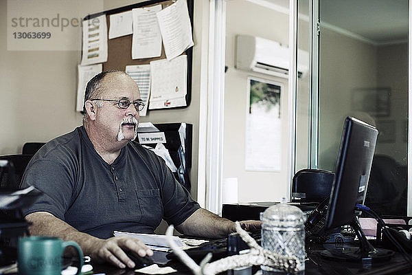 Mann arbeitet am Desktop-Computer im Büro