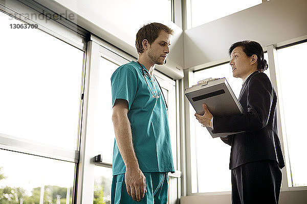 Geschäftsfrau bespricht Dokument mit Arzt  während sie im Krankenhaus steht