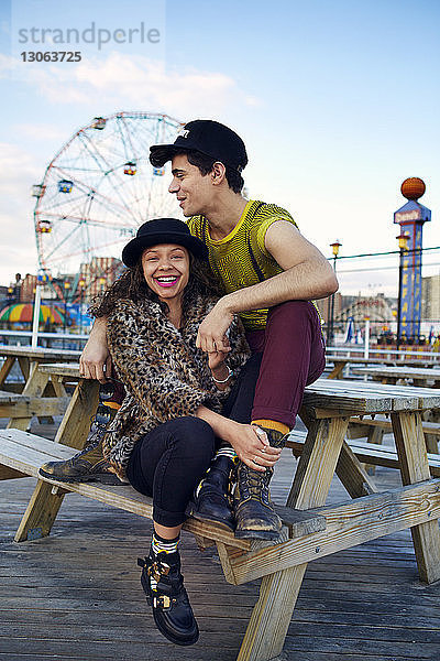 Glückliche Freunde sitzen auf Coney Island am Picknicktisch