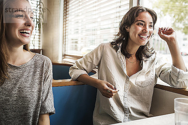 Lächelnde Freunde unterhalten sich  während sie im Restaurant sitzen