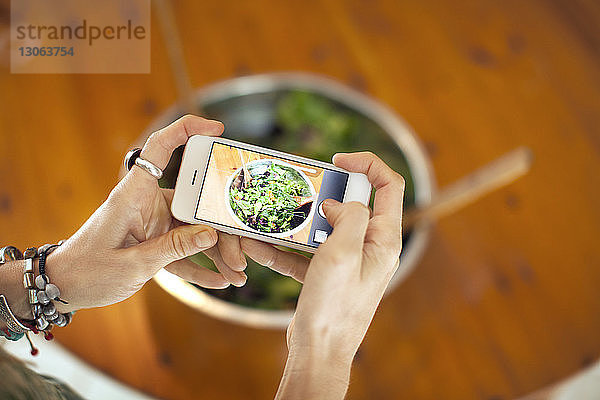 Beschnittenes Bild einer Frau  die Salat in einer Schüssel fotografiert