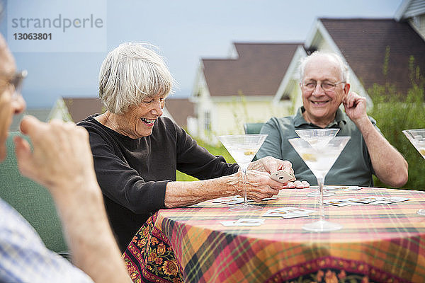 Freunde spielen Karten  während sie am Tisch sitzen