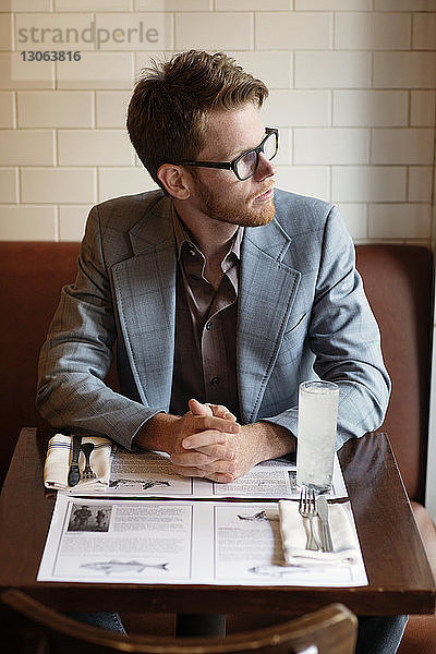 Nachdenklicher Mann schaut weg  während er am Tisch im Restaurant sitzt