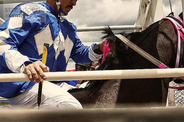 Ausgeschnittenes Bild eines Mannes  der auf einem Pferd bei einem Wettbewerb sitzt