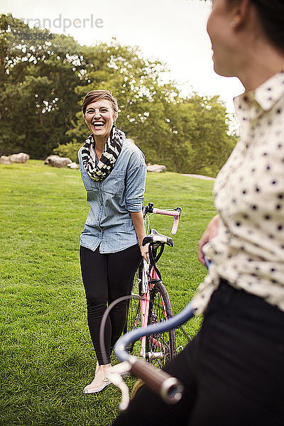 Glückliche Frauen mit Fahrrädern stehen auf einem Feld im Central Park