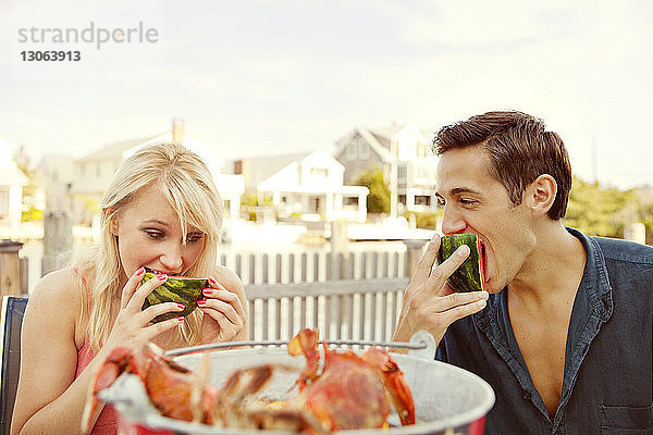 Paar isst Wassermelone  während es im Hinterhof sitzt