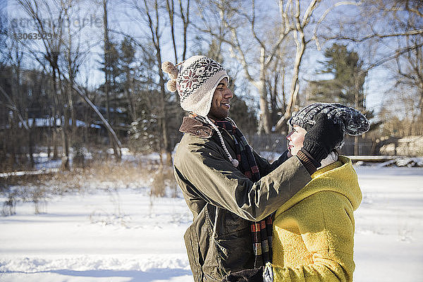 Seitenansicht eines Mannes  der eine Strickmütze zu einer Frau trägt  während er auf einem schneebedeckten Feld steht