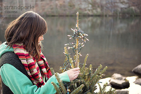 Frau schmückt Weihnachtsbaum am Seeufer