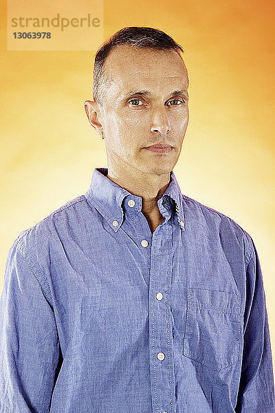 Porträt eines selbstbewussten Mannes vor orangem Hintergrund