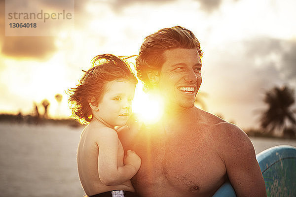 Vater und Sohn schauen weg  während sie am Strand stehen