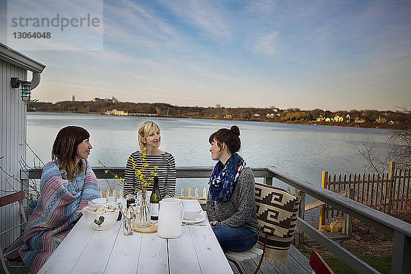 Freunde unterhalten sich im Winter beim Essen auf der Veranda am See