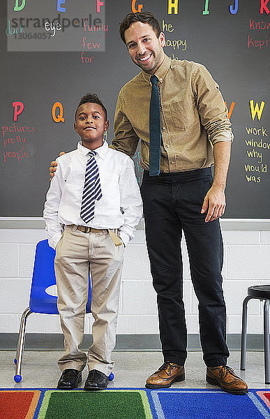 Porträt eines Lehrers und Schülers im Klassenzimmer vor der Tafel stehend