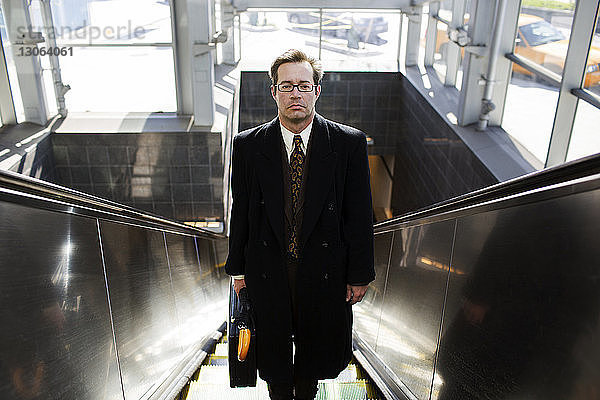 Porträt eines auf der Rolltreppe stehenden Geschäftsmannes