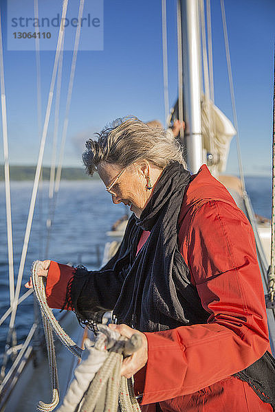 Seitenansicht einer älteren Frau  die ein Seil in einer Yacht auf See hält