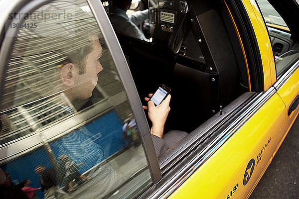 Geschäftsmann benutzt Smartphone während einer Taxifahrt