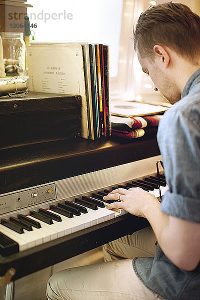 Seitenansicht eines Mannes  der zu Hause Klavier spielt