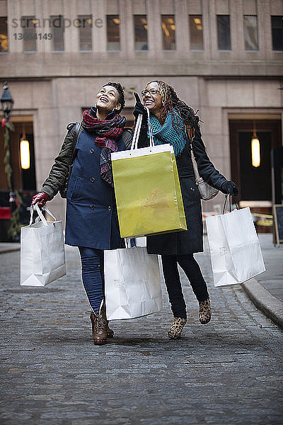 Glückliche Frauen halten Einkaufstüten  während sie auf der Straße stehen