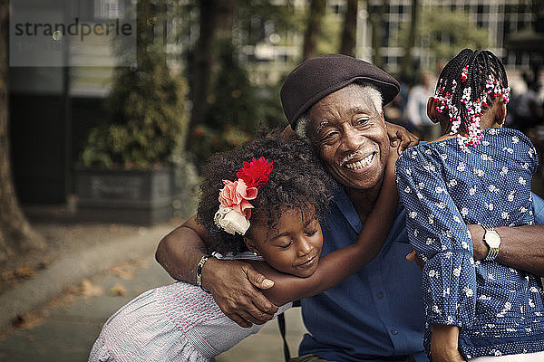 Glücklicher Großvater umarmt Enkelkinder  während er in der Stadt steht