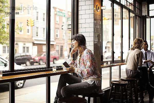 Frau hält Buch  während sie in der Bar sitzt
