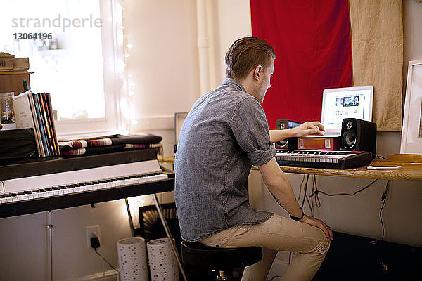 Seitenansicht eines Mannes mit Klavier mit Laptop-Computer