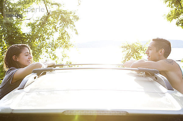 Seitenansicht eines Paares  das sich auf einem Auto an den See lehnt