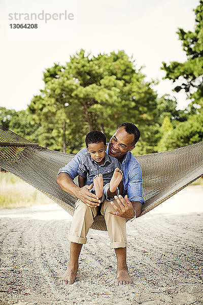 Glücklicher Vater und Sohn entspannen sich auf einer Hängematte im Garten