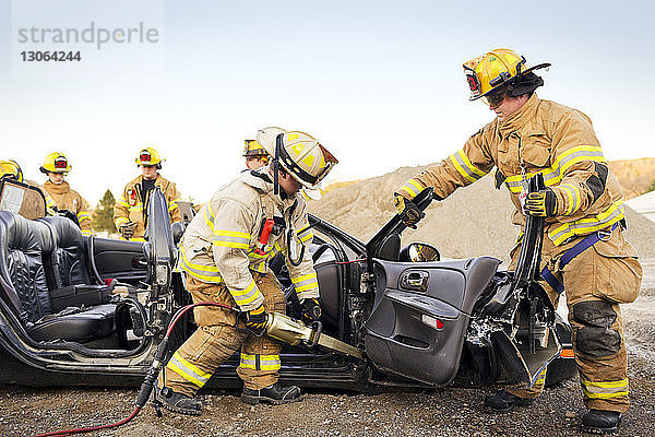 Feuerwehrmänner schneiden Auto bei Übungsübung auf
