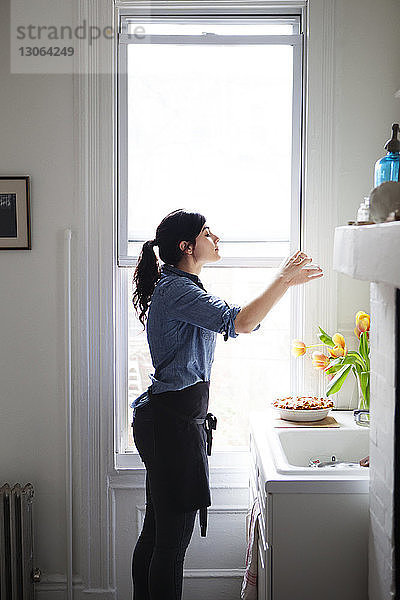 Seitenansicht einer Frau  die gebackenen Kuchen über das Telefon zu Hause fotografiert