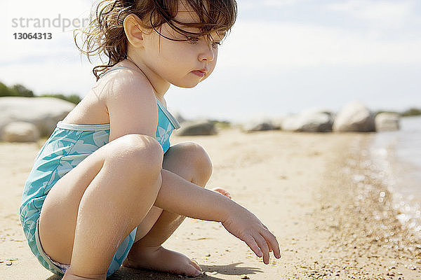 Seitenansicht eines Mädchens  das am Strand am Ufer spielt
