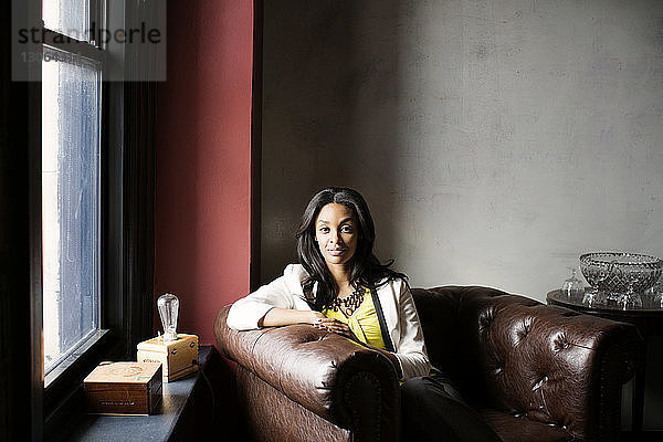 Porträt einer selbstbewussten Frau  die im Büro auf einem Sessel sitzt