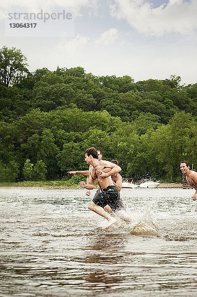 Freunde spielen Fussball im Fluss