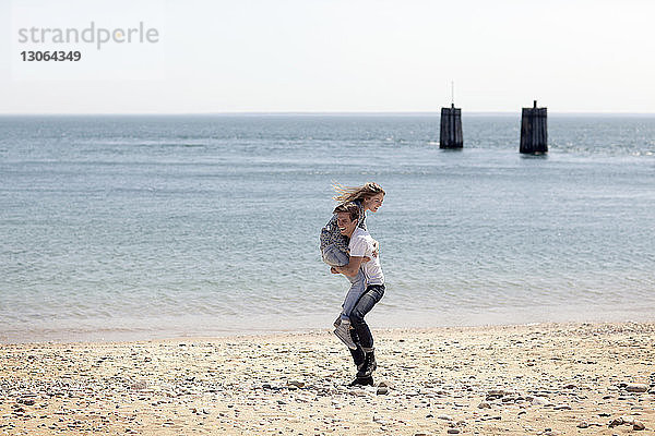 Mann hebt Freundin hoch  während er am Strand steht