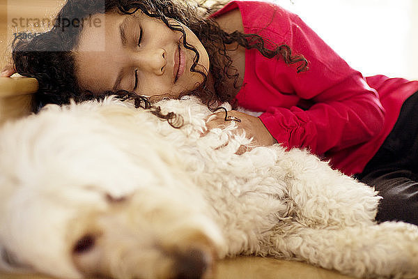Mädchen schläft mit Hund auf dem Boden