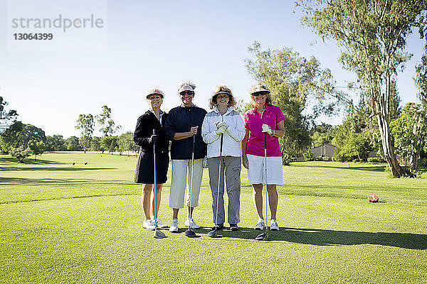 Porträt von glücklichen Freunden am Golfplatz stehend