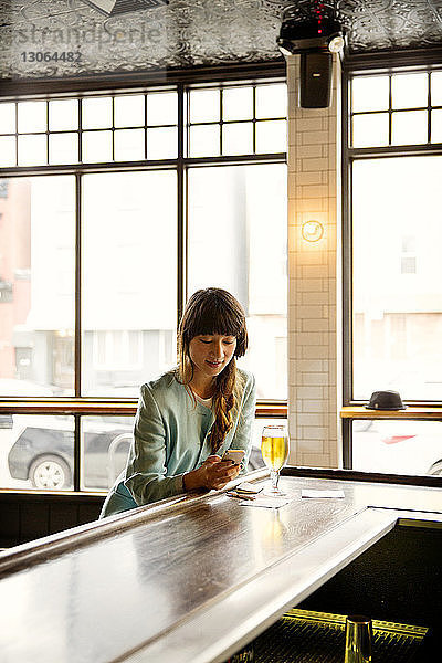 Frau benutzt Mobiltelefon  während sie in einer Bar sitzt