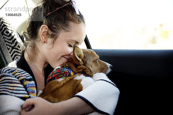 Frau umarmt Hund  während sie im Auto sitzt