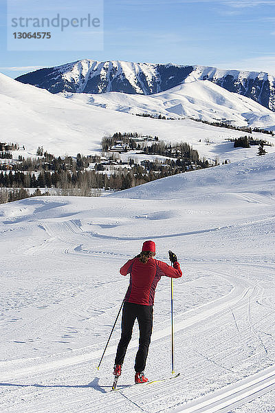 Rückansicht einer Frau beim Skifahren auf schneebedecktem Feld