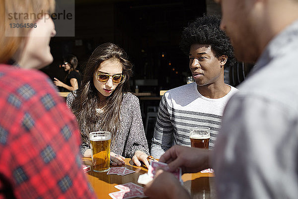 Freunde spielen Karten bei einem Bier am Tisch in einer Brauerei